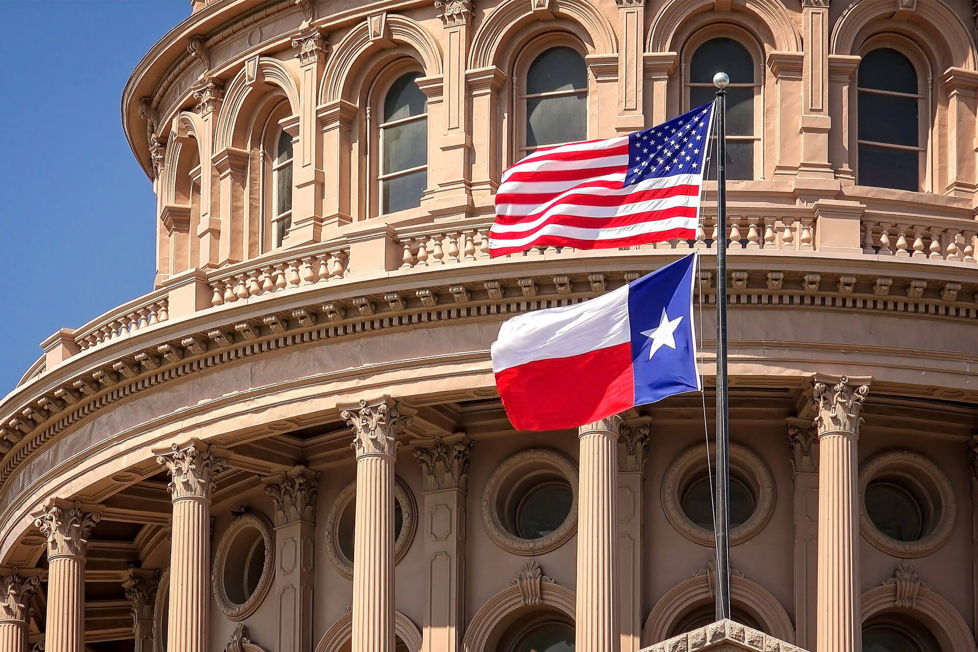 USA and Texas flags flying on the dome of the Texas State Capitol building of Austin