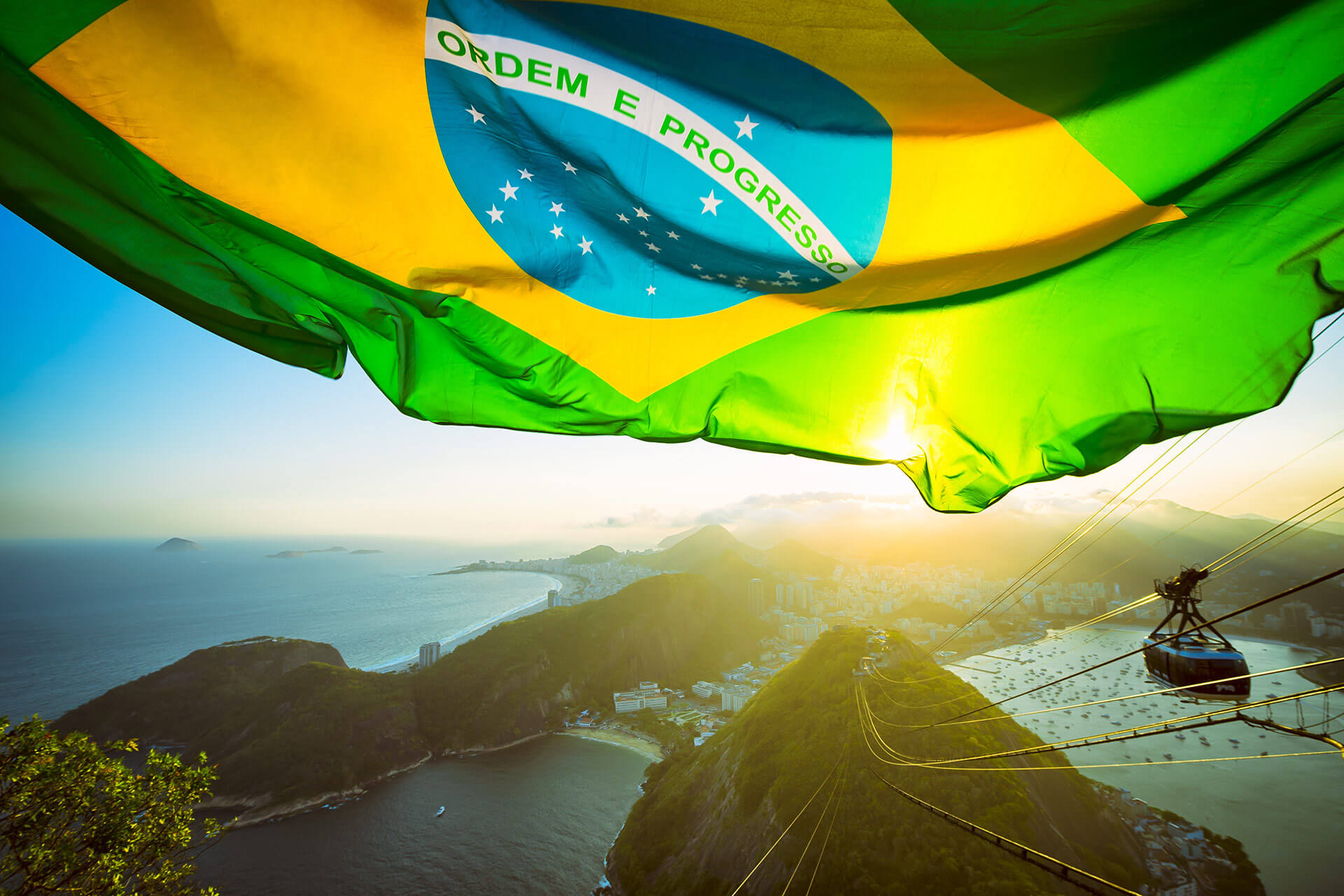 Brazilian flag over golden sunset city skyline at Sugarloaf Mountain in Rio de Janeiro