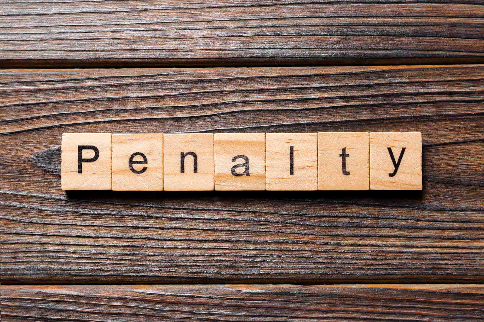 wooden letter tiles spelling the word penalty