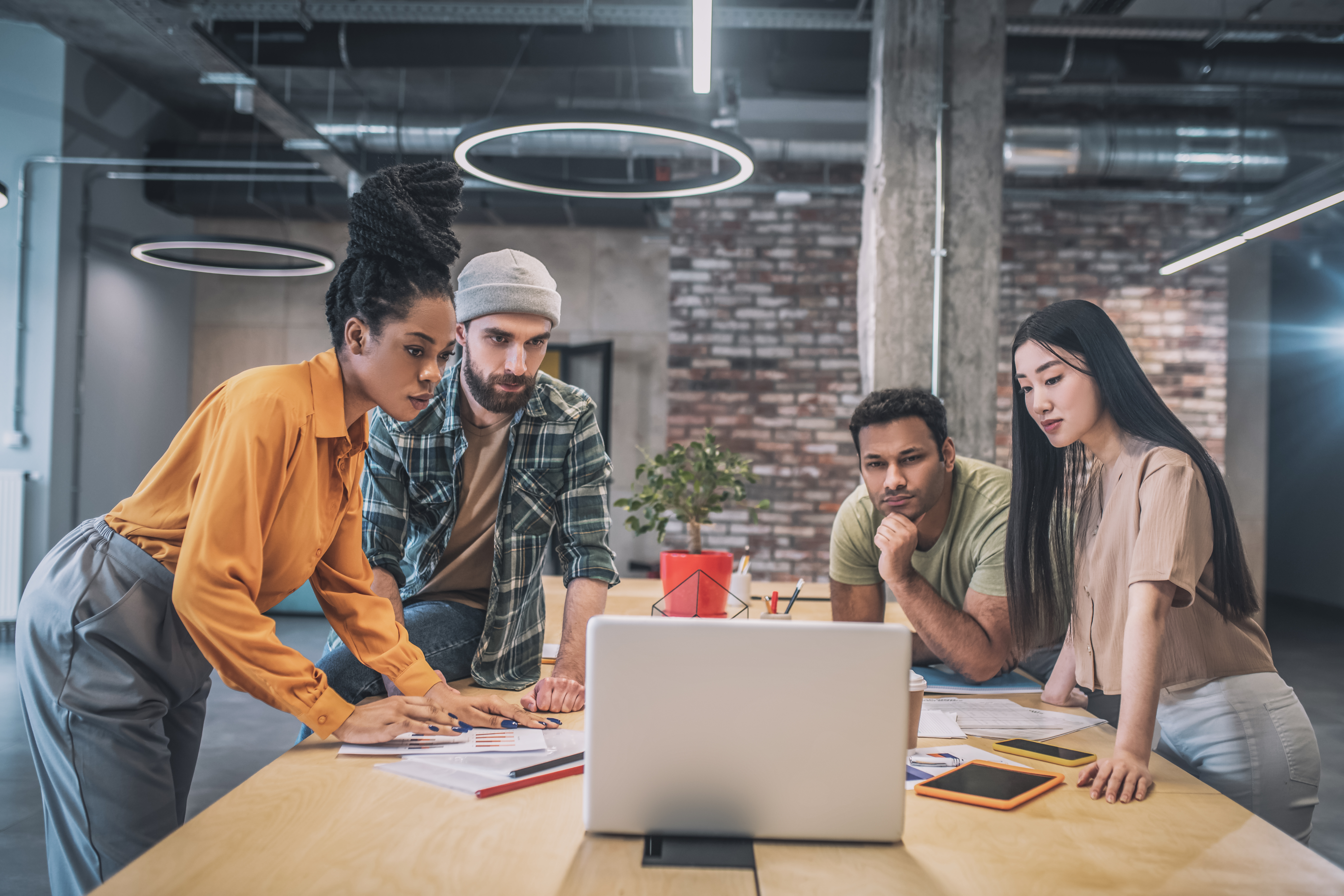 4 persons sitting in meeting room looking at laptop screen