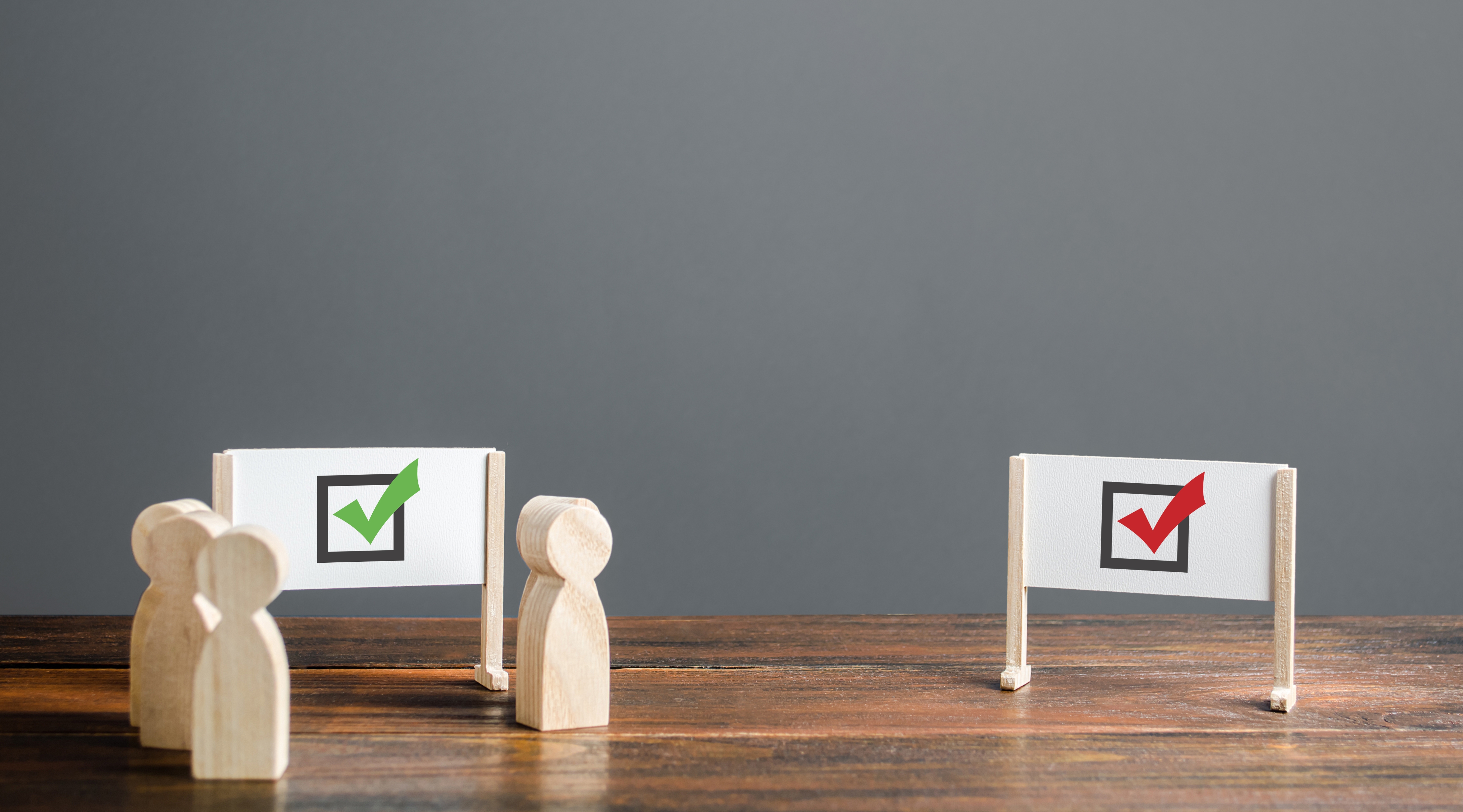 wooden figurines next to signs that show a green and a red checkmark